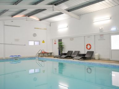 An indoor pool area with lounge chairs and safety equipment at Columbine Cottage in Bude