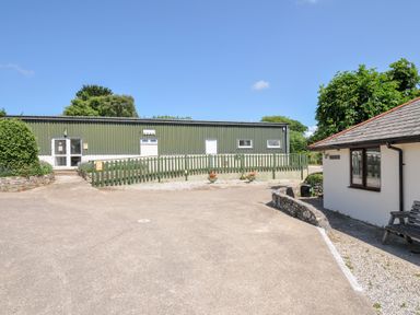 An outdoor view of a green building and a white building at Columbine Cottage in Bude