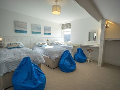 A bedroom with three single beds blue bean bags a dressing table and stool at Argoed in Abersoch