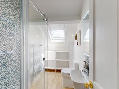 A bathroom with a toilet sink mirror glass shower and shelving at Argoed Abersoch