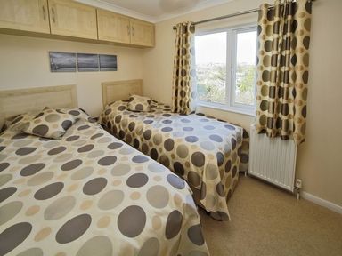 A bedroom with two single beds with polka dot bedspreads and matching curtains at Arwelfa Lodge in Abersoch