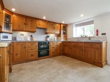A kitchen with wooden cabinets and appliances at Bryn Awel in Mynytho near Abersoch