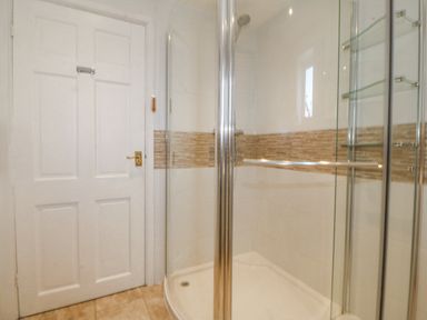A bathroom with a shower and door at Bryn Awel in Mynytho near Abersoch