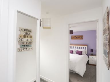 A hallway leading to a bedroom with a bed and nightstand at Bywyd Da 232 Cae Du in Abersoch