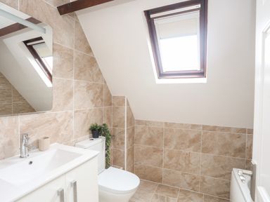 A bathroom with a sink cabinet mirror toilet and skylight window at Bywyd Da 232 Cae Du in Abersoch