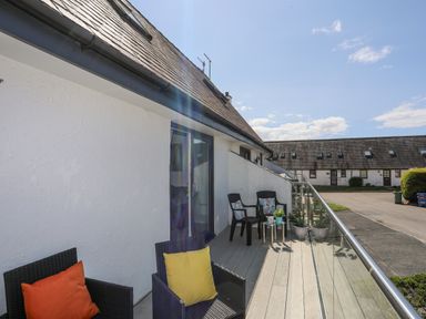 A balcony with black chairs and colorful cushions at Bywyd Da 232 Cae Du in Abersoch