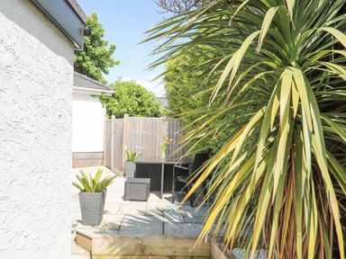 A patio area with outdoor furniture and plants surrounded by a wooden fence at Bywyd Da 232 Cae Du in Abersoch