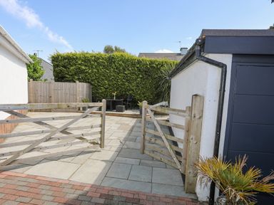 An outdoor patio area with wooden gates paving and a table with chairs and plants at Bywyd Da (232 Cae Du) in Abersoch