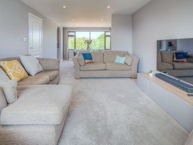 A living room with two sofas a large window and a television at Cromlin Glas in Abersoch