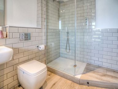 A bathroom with a toilet sink and glass shower enclosure at Cromlin Glas in Abersoch