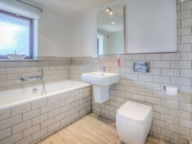 A bathroom with a bathtub sink toilet and a wall mirror at Cromlin Glas in Abersoch