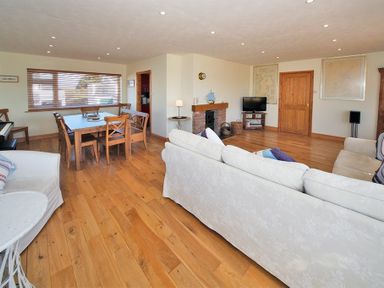 A living room with white sofas wooden dining table chairs fireplace and television at Eleri in Abersoch