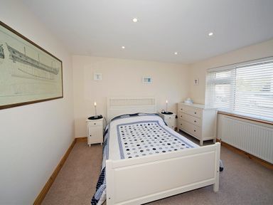 A bedroom with a double bed two bedside tables with lamps a dresser and a window with blinds at Eleri in Abersoch