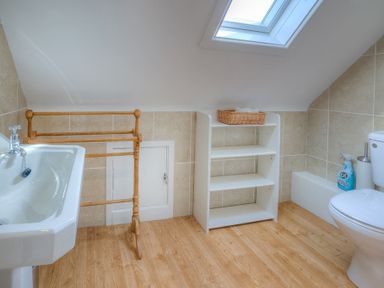 A bathroom with a sink wooden towel rack white shelving unit and a toilet at Gilfach in Abersoch