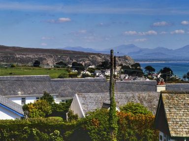 A view of rooftops with hills in the background and the sea on the side at Gilfach in Abersoch