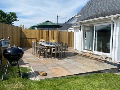 An outdoor patio with a dining table and grill at Gilfach in Abersoch