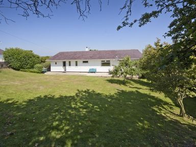 A single-story white house with a lawn and trees in the yard at 3 Madoc View in Bwlchtocyn near Abersoch