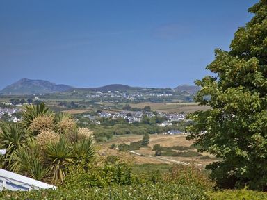 A landscape view of houses and fields with trees and hills in the background at 3 Madoc View in Bwlchtocyn near Abersoch