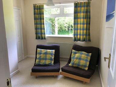 A small room with two chairs and matching cushions under a window with plaid curtains at 3 Madoc View Bwlchtocyn near Abersoch
