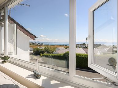 A view through open windows overlooking houses trees fields and the sea at The Anchorage in Abersoch