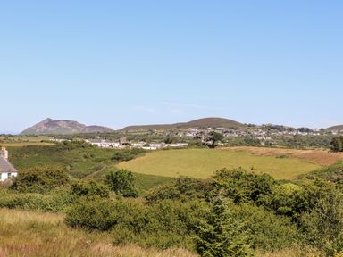 A countryside landscape with green fields bushes scattered houses and hills in the background at The Anchorage in Abersoch