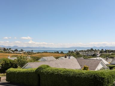 A coastal village with houses fields and sea with mountains in the background at The Anchorage in Abersoch