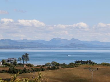 A coastal landscape with houses trees and hills overlooking a body of water at The Anchorage in Abersoch