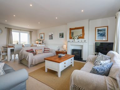A living room with sofas a coffee table a dining table and a fireplace at The Anchorage in Abersoch