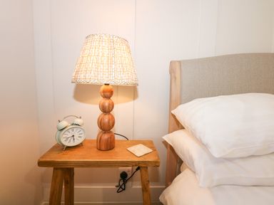 A bedside table with a lamp and an alarm clock next to a bed at The Anchorage in Abersoch