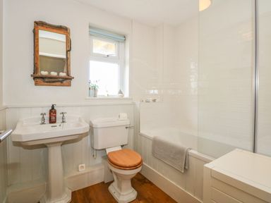 A bathroom with a sink mirror toilet bathtub and window at The Anchorage in Abersoch