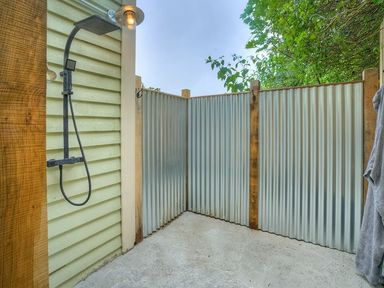 An outdoor shower area with a black shower fixture and corrugated metal walls at The Coach House in Abersoch
