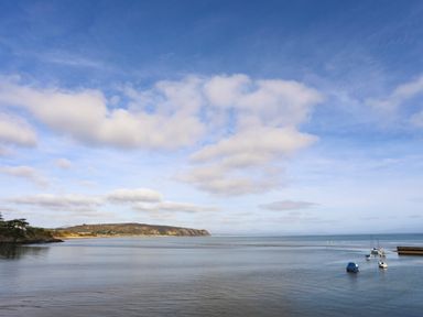 A coastal scene with boats anchored on calm water and a distant headland at The Warren D26 in Abersoch