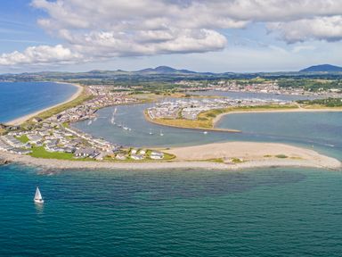 A coastal area with houses near the shore a marina with boats and hills in the background at The Warren D26 in Abersoch