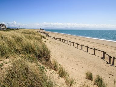 A sandy beach with wooden fencing and grass dunes by the sea at The Warren D26 in Abersoch