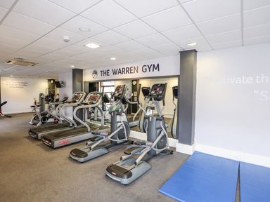 A gym with treadmills elliptical machines exercise bikes and blue exercise mats at The Warren D26 in Abersoch