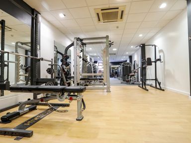 A gym room with weightlifting benches mirrors and exercise machines at The Warren D26 in Abersoch