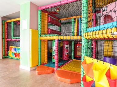 An indoor children's play area with padded climbing structures and nets at The Warren D26 in Abersoch