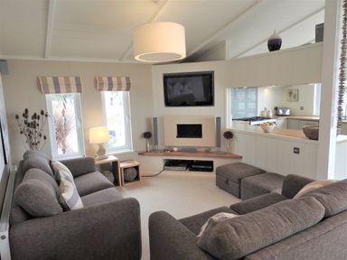 A living room with two gray sofas a wall-mounted TV and a fireplace at The Warren D26 in Abersoch