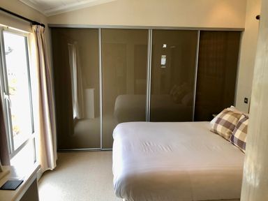 A bedroom with a bed with checkered pillows and sliding closet doors at The Warren D26 in Abersoch