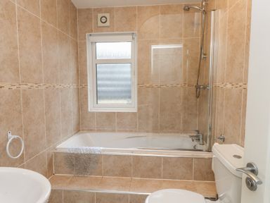 A bathroom with a bath tub, shower, toilet, and sink at The Warren D7 Abersoch