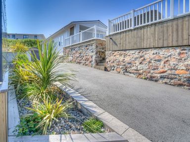 A driveway beside a stone wall with plants along the edge at The Warren Q4 in Abersoch