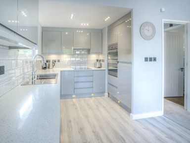 A modern kitchen with white cabinets a sink stove and built in ovens at The Warren Q4 in Abersoch