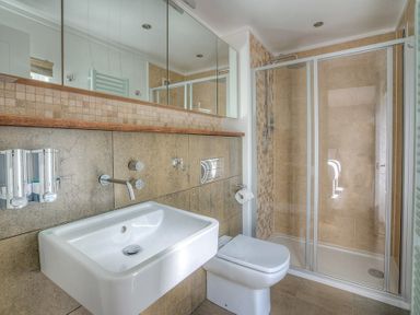 A bathroom with a sink toilet and glass shower enclosure at The Warren Q4 in Abersoch