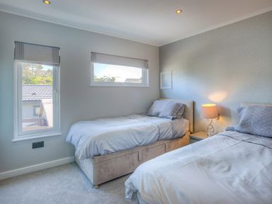 A bedroom with two single beds a bedside table and a lamp at The Warren Q4 in Abersoch
