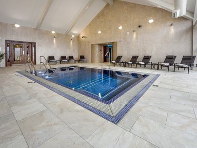 An indoor pool with chairs and towels along the walls at The Warren Q4 in Abersoch