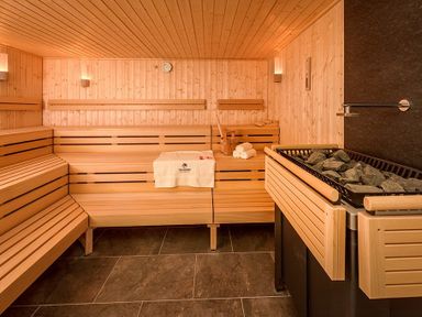 An interior view of a wooden sauna room with benches stones and towels at The Warren Q4 in Abersoch