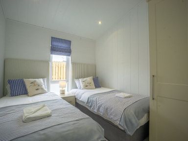A bedroom with two single beds and a nightstand between them at The Warren T23 in Abersoch