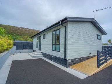 An exterior view of a modular home with steps and a wooden ramp outside at The Warren T23 in Abersoch