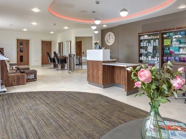 A salon lobby with a reception desk chairs mirrors and flowers at The Warren T23 in Abersoch