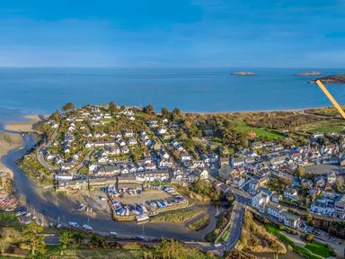 An aerial view of a coastal village with houses boats docked in a small harbor and a road near the shoreline at Ty Coed in Abersoch